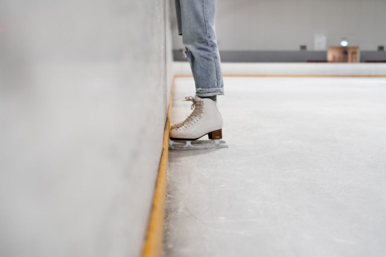 a human stands in ice skates with their toes against the wall