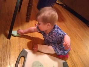 Small child plays with edible play dough on the floor.