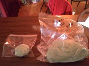 2 bags of edible play dough, one large and one small. The large one has the date on it.