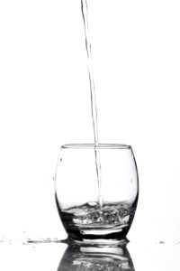 Water is poured from above in a single stream into a clear class.