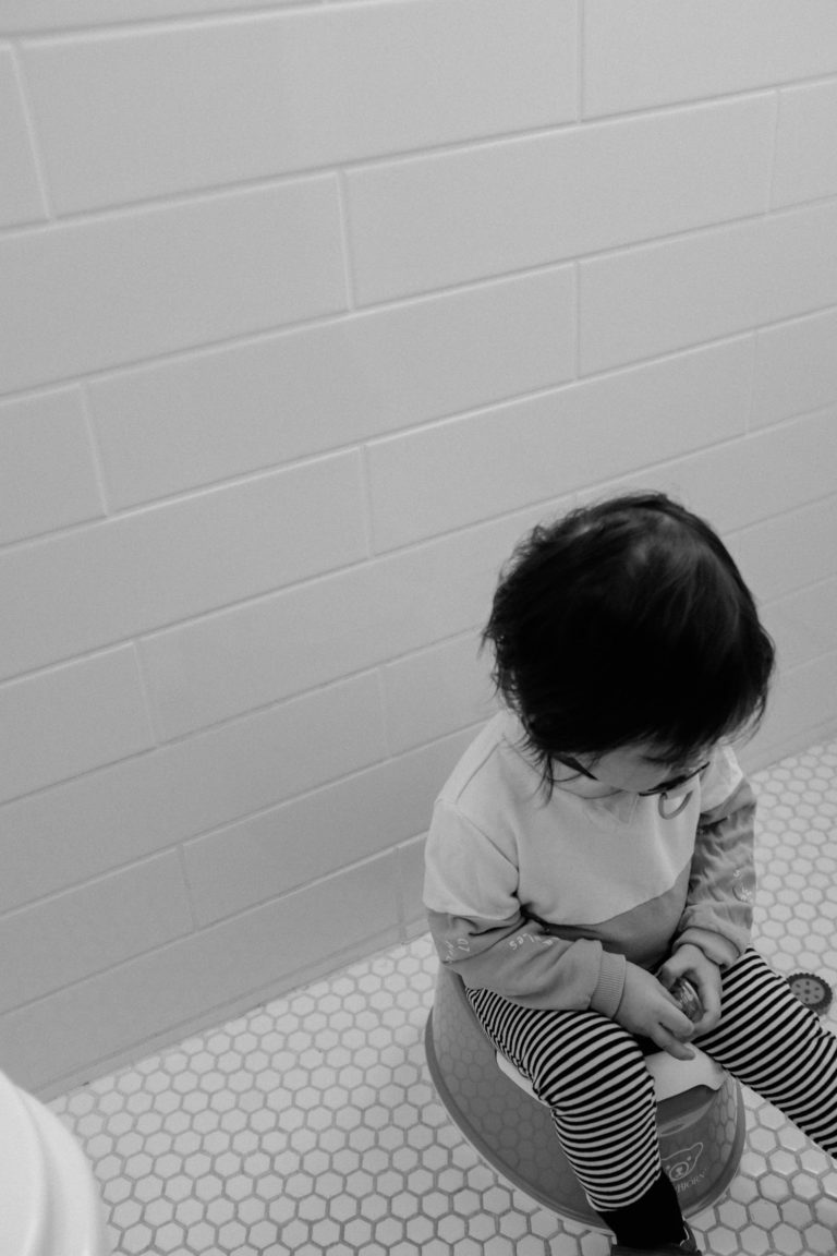 A child its on the potty while wearing pants