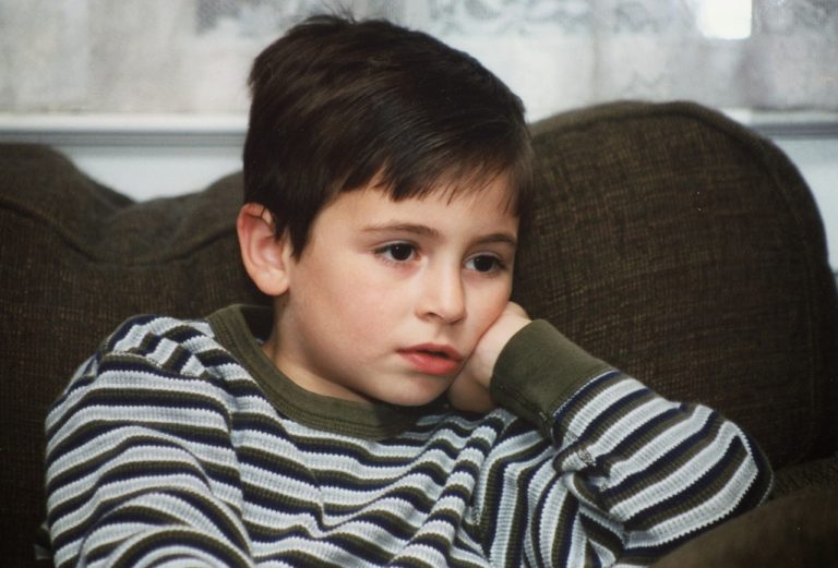 young boy with vacant glassy eyed look, presumably watching TV
