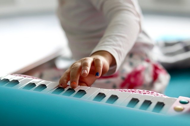 A child's painted fingers play the piano