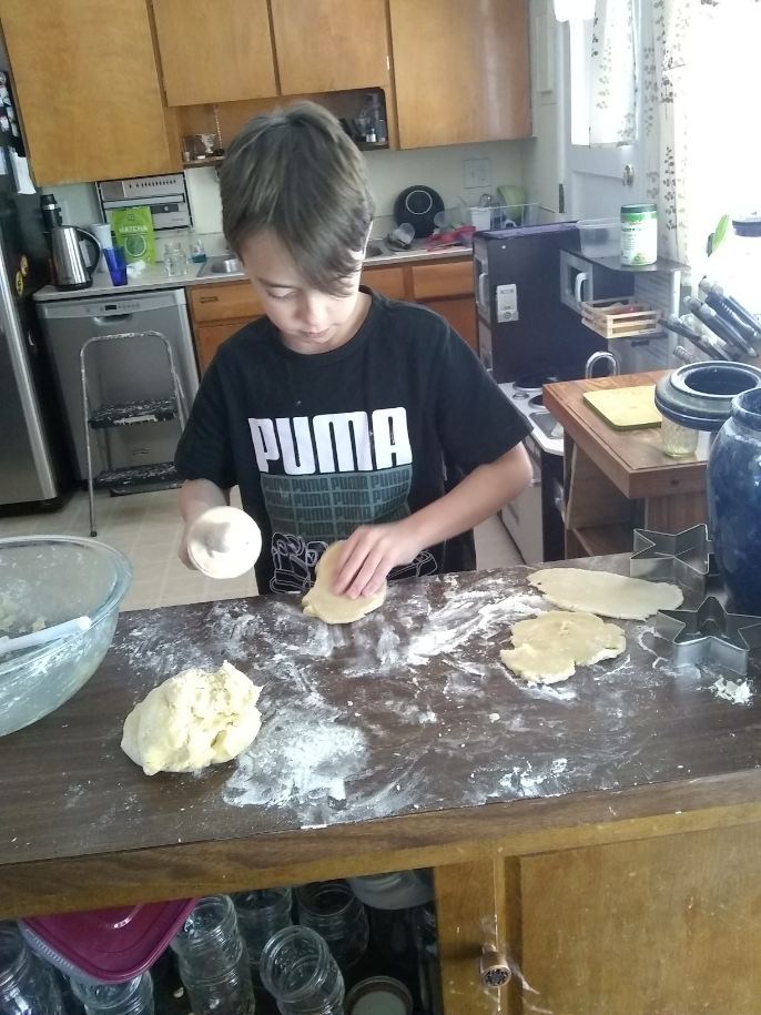 Child rolls out cookie dough on the counter