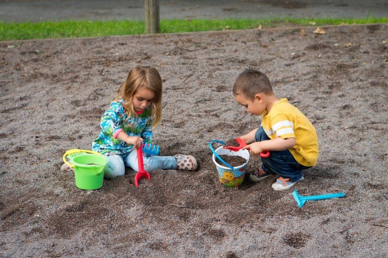 Two children play together in a sandbox