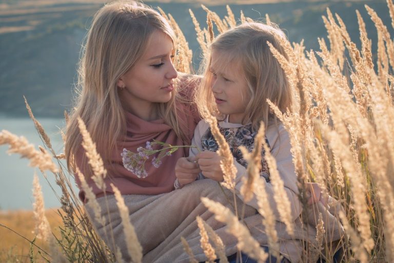 Mother and daughter sit in wheat together