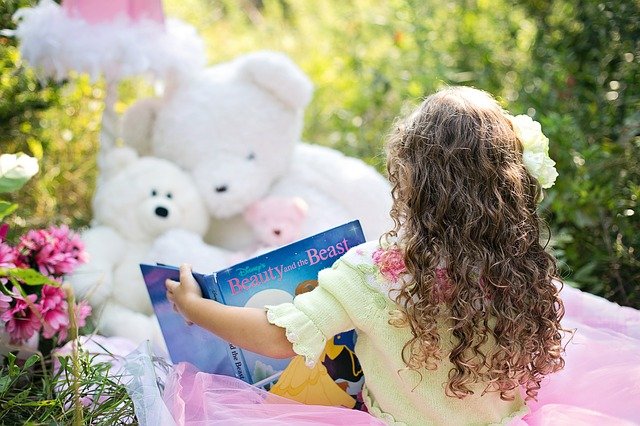 A young child reads a book to their stuffed animals