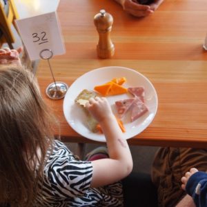 Child sits at table with plate of cheese and crackers