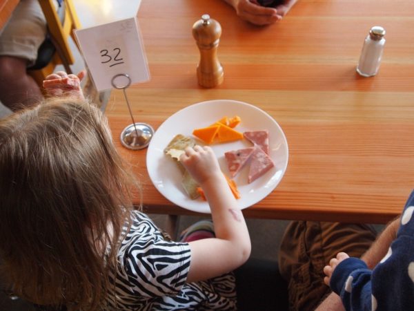 Child sits at table with plate of cheese and crackers