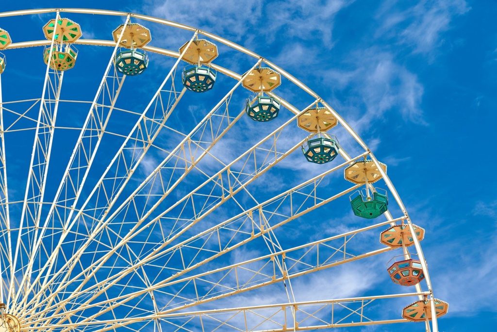 A ferris wheel is light against a bright blue sky