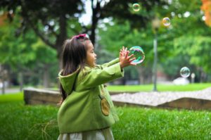 A child reaches for bubbles floating in the air
