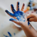 A child's hand is covered in blue paint