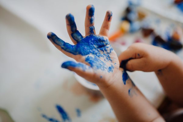 A child's hand is covered in blue paint